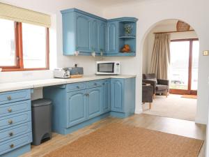 a kitchen with blue cabinets and a microwave at Awelfryn in Rhosneigr