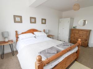 a bedroom with a wooden bed and a wooden dresser at Awelfryn in Rhosneigr