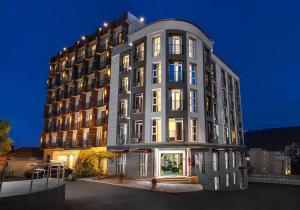 un edificio alto gris con luces encendidas en Hotel Grand Palace, en Tiflis