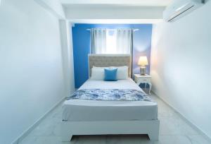 um quarto com uma cama branca e uma parede azul em Serene 2 & 1 with Amazing Views em Las Flores