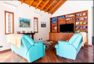 uma sala de estar com duas cadeiras azuis e uma televisão em Casa na Granja Viana - Cotia em Cotia
