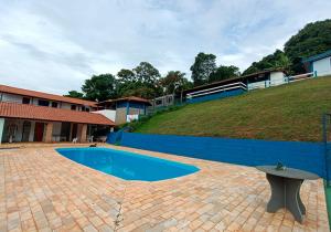 a swimming pool with a bench in front of a building at Rancho Morada do Sol in Areado