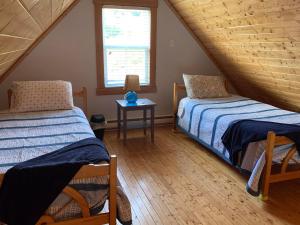 ein Dachgeschosszimmer mit zwei Betten und einem Fenster in der Unterkunft Net Loft Cottage in Twillingate