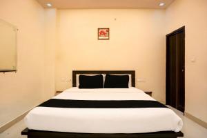 a bedroom with a large white bed with black pillows at OYO Flagship Hotel Sky Inn in Chinhat