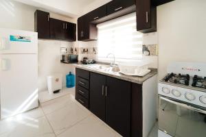 Las Flores的住宿－Stylish 2 bed 1 bath Sleeps 4，厨房配有黑色橱柜和白色冰箱。