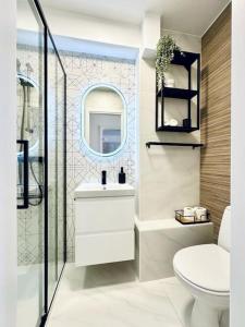 een badkamer met een toilet, een wastafel en een spiegel bij City Center Apartment With Balcony in Timişoara