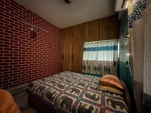 - une chambre avec un lit et un mur en briques dans l'établissement Amma’s Om stay, à Patna
