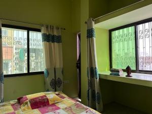 a bedroom with a bed and two windows at Amma’s Om stay in Patna