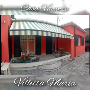 un edificio rosso con tenda da sole e fiori in vasi di VILLETTA MARIA a Guanzate