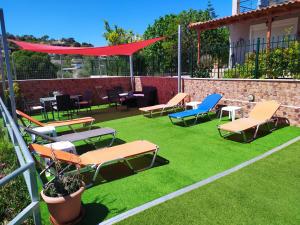 a patio with chairs and tables on grass at Thalassa in Panayía