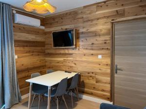 a dining room with wooden walls and a table and chairs at GITE PEI LA VANILLE Duplex Bord de Nature in Sainte-Suzanne
