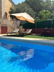 a swimming pool with an umbrella and a table and chairs at Maison des Hortensias in El Vendrell