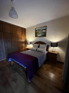 um quarto com uma cama grande com lençóis e almofadas roxos em Casa do Eirô em Resende