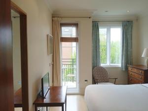 a hotel room with a bed and a desk and a window at Beautiful apartment in Kew, Richmond London with Free Underground Parking in London