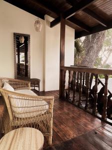 a porch with wicker chairs and a wooden floor at Hotel Perla de la Playa in Tamarindo