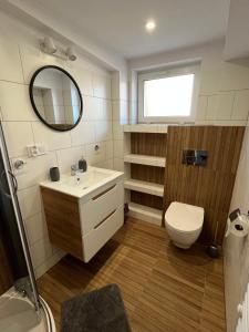 ein Badezimmer mit einem Waschbecken, einem WC und einem Spiegel in der Unterkunft Apartament ~ Nad Zatoką in Jastarnia