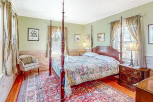 1 dormitorio con cama con dosel y silla en Cove Cottage en East Falmouth