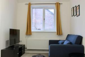 ein Wohnzimmer mit einem blauen Stuhl und einem Fenster in der Unterkunft Modern Guest Lodge, Centrally Located, Free Parking, 8 Min to LGW Airport in Crawley