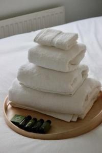 a pile of towels on a plate on a bed at Modern Guest Lodge, Centrally Located, Free Parking, 8 Min to LGW Airport in Crawley