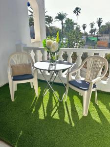 two chairs and a table with a vase of flowers on a balcony at Sunny Sea View Apartment Center of Las Americas in Playa de las Americas
