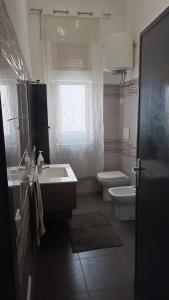 ein Bad mit einem Waschbecken, einem WC und einem Fenster in der Unterkunft APPARTAMENTO Fiori di MELOGRANO in Trapani