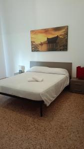 ein großes Bett in einem Schlafzimmer mit einem Bild an der Wand in der Unterkunft APPARTAMENTO Fiori di MELOGRANO in Trapani