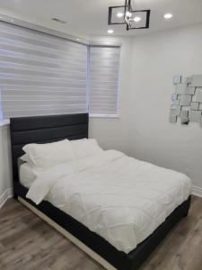 um quarto com uma cama com lençóis brancos e uma janela em Upscale 2BR Condo - Near Miliken District Park em Markham