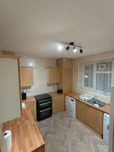 uma cozinha com armários de madeira e um fogão preto em Spacious 3 bed flat opp Springfield park, Hackney. em Londres