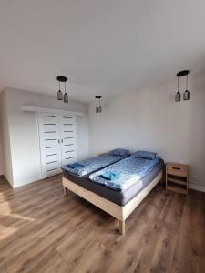 een slaapkamer met een bed en een houten vloer bij Apartament w centrum Radomia in Radom