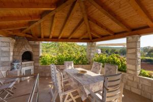 Un patio al aire libre con mesa y sillas y una chimenea. en Holiday Home Trojkovic, en Dubrovnik