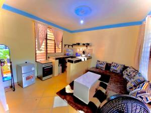ein Wohnzimmer mit einem Sofa und einer Küche in der Unterkunft Cozy Holiday Homes. in Ukunda