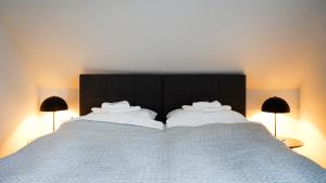 uma cama grande com lençóis brancos e duas lâmpadas em SI-View Doppelzimmer Zimmer 23 em Siegen