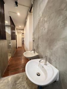 2 lavabos blancos en un baño con suelo de madera en House Ju en Bangkok