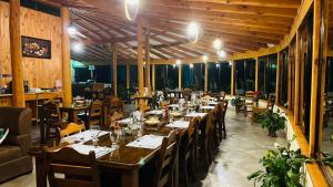 a restaurant with a long table with chairs and tablesearcher at El Toucanet Lodge in El Copey