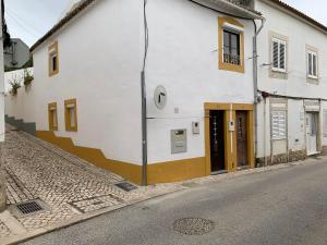 un bâtiment blanc avec des portes brunes dans une rue dans l'établissement Casa Touriga, à Arruda dos Vinhos