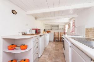 a kitchen with white cabinets and orange pots at Blue Cottage - 3 bedroom cottage in Feock in Feock