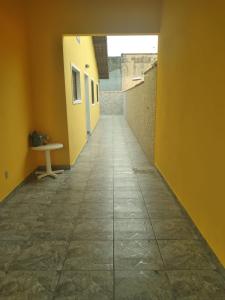 an empty hallway with a yellow wall and a table at Casa Itanhaem in Itanhaém