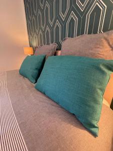 Una cama con dos almohadas verdes encima. en Domaine La Belle Histoire - Gîte côté Parc en Besset