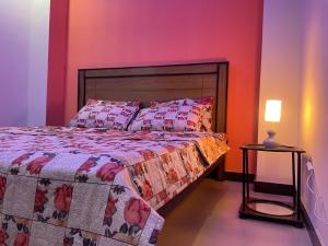 a bedroom with a bed and a table with a lamp at Own It Apartment Brown in Islamabad