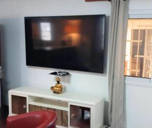 ein Wohnzimmer mit einem TV und einem roten Stuhl in der Unterkunft Appartement Soleil,Batterie 4 in Libreville