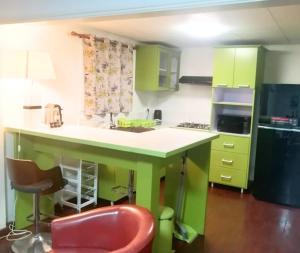 a kitchen with green cabinets and a red chair at Appartement Soleil,Batterie 4 in Libreville