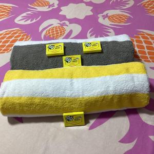 twee handdoeken met gele labels op een bed bij Chambre chez Kim in Taputapuapea