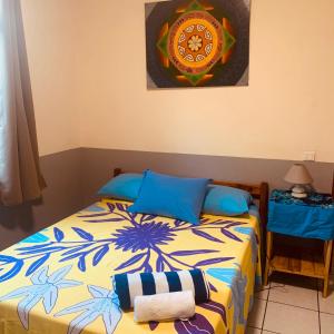 een slaapkamer met een bed met blauwe kussens bij Chambre chez Kim in Taputapuapea