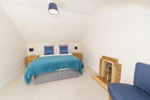 a bedroom with a bed and two blue chairs at Achloist Holiday Cottage in Drumbeg