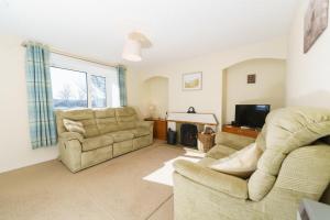 a living room with two chairs and a couch and a television at Achloist Holiday Cottage in Drumbeg