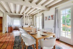 uma sala de jantar com uma mesa de madeira e cadeiras brancas em Bourgeois house and idyllic garden em Le Thuit-Simer