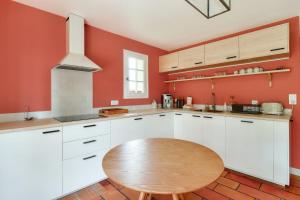 uma cozinha com armários brancos e uma mesa de madeira em Bourgeois house and idyllic garden em Le Thuit-Simer