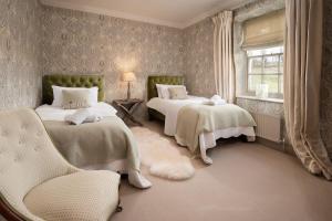 a bedroom with two beds and a chair and a window at Broadgate Farmhouse in West Woodburn