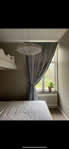 a bedroom with a bed with a curtain and a window at Café Mandeltårtan B&B VillaFloraViola in Ronneby