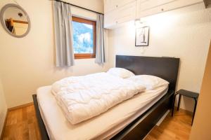 a bedroom with a bed with a white comforter at Résidence Les Portes De La Vanoise - 2 Pièces pour 6 Personnes in Villarodin-Bourget